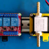 Physical DIN rail clip mounts holding a relay and solenoid on a metal DIN rail