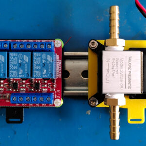 Physical DIN rail clip mounts holding a relay and solenoid on a metal DIN rail